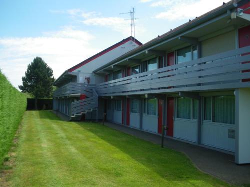 a building with a grass yard in front of it at Initial by balladins Dieppe in Saint-Aubin-sur-Scie