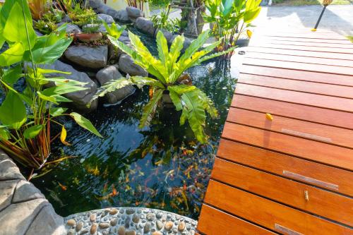 a koi pond in a garden with a wooden deck at Nature Line Resort in Khanom