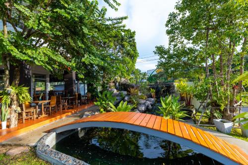 a bridge over a pond in a garden at Nature Line Resort in Khanom