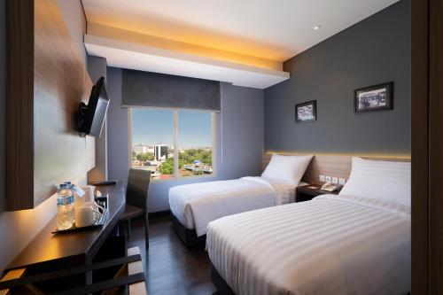 a hotel room with two beds and a window at BATIQA Hotel Darmo - Surabaya in Surabaya