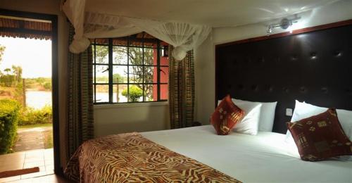 a bedroom with a large bed and a window at Mara River Lodge in Aitong
