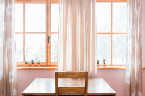 a table and a chair in a room with windows at Farm hostel - The house in Elektrėnai