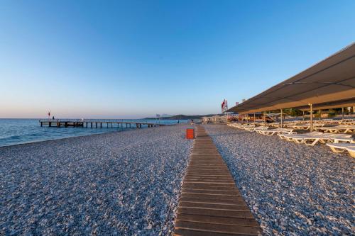 a sandy beach with lounge chairs and a pier at Armas Labada in Kemer