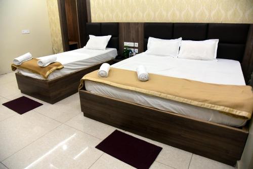 two twin beds in a room with mats on the floor at Hotel Guru Estate in Puri