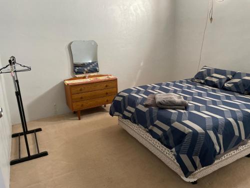 1 dormitorio con cama, tocador y espejo en J's Hardware & Gifts, en Perenjori