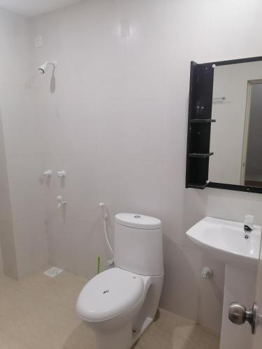 a white bathroom with a toilet and a sink at The Rose Garden House, Addu City, Maldives in Hithadhoo
