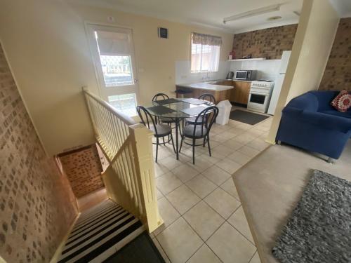 a living room with a table and chairs and a kitchen at Avaleen Lodge Motor Inn in Nowra