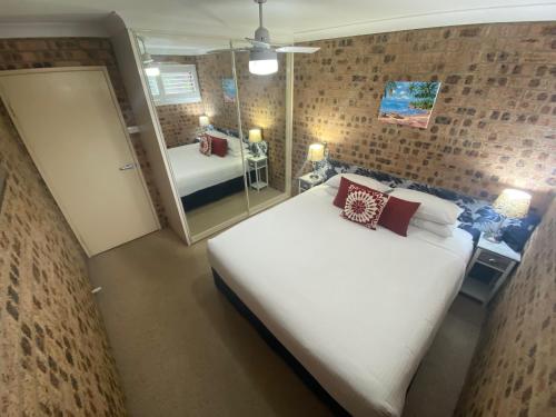 Avaleen Lodge Motor Inn في ناورا: غرفة نوم بسرير ابيض كبير ومرآة