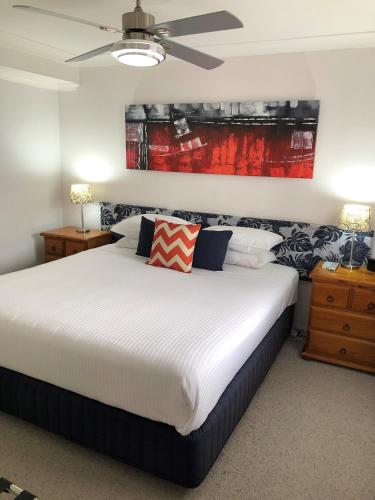 a bedroom with a bed and a painting on the wall at Avaleen Lodge Motor Inn in Nowra