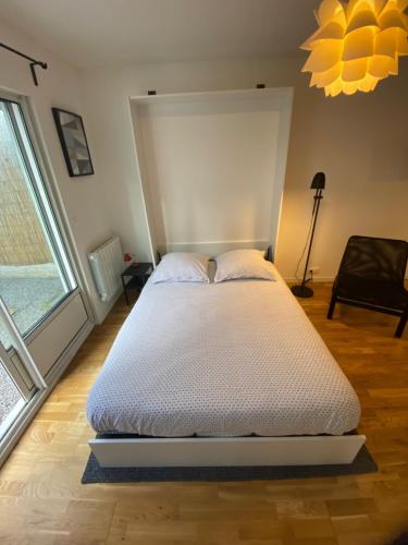 ein großes Bett in einem Zimmer mit einem großen Fenster in der Unterkunft Grand studio de 38m2 et cour indépendante de 25m2 dont wifi et Netflix in Montpellier