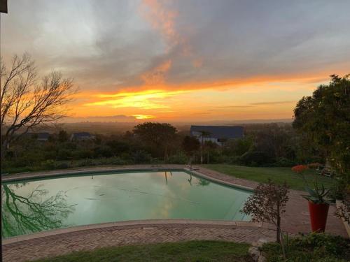 una piscina con puesta de sol en el fondo en Watermill Studios en Gordonʼs Bay