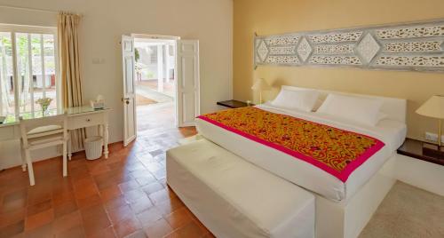 a bedroom with a large bed and a desk and a door at Nyne Hotels Rock Villa - Bentota in Bentota