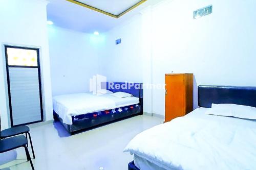 1 Schlafzimmer mit 2 Betten und einem Fenster in der Unterkunft Minang Raya Guesthouse Syariah RedPartner in Siulakmukai