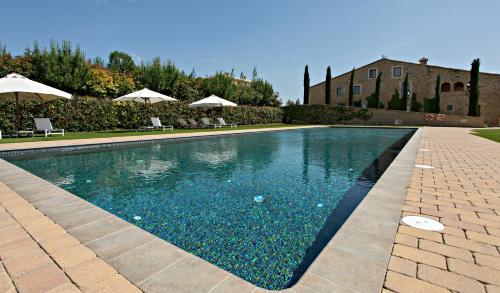 a swimming pool with chairs and umbrellas next to a building at Casa Anamaria Hotel in Ollers