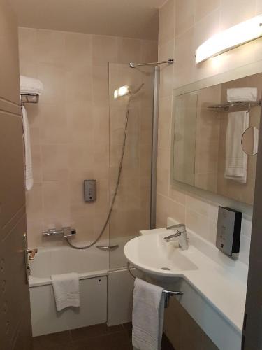 a bathroom with a sink and a shower with a mirror at Logis Hôtel La Fauceille in Perpignan