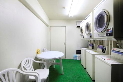 Monthly Mansion Tokyo West 21 - Vacation STAY 10889 في فوتشو: غرفة مع طاولة وغسالة ملابس