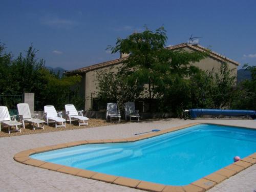 a swimming pool with chairs and a house at Le Cévenn'hols in Le Vigan