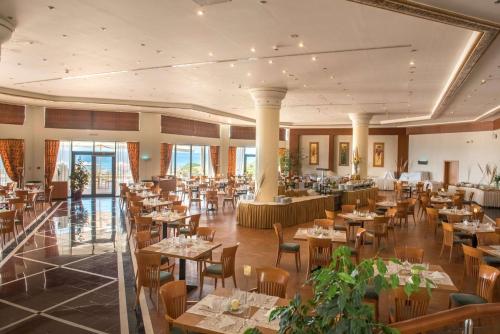 a restaurant with tables and chairs in a room at Ramada Plaza by Wyndham Thraki in Alexandroupoli
