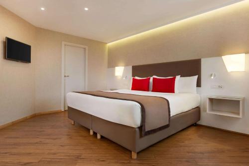 a large bedroom with a large bed with red pillows at Ramada Plaza by Wyndham Thraki in Alexandroupoli