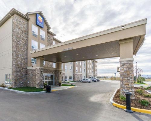 Comfort Inn & Suites Edmonton International Airport في نيسكو: مبنى الفندق مع وجود سيارة متوقفة في موقف للسيارات