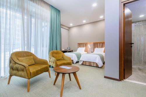 um quarto de hotel com duas camas e uma cadeira e uma mesa em Best Western Tbilisi City Center em Tbilisi