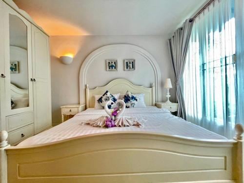 a bedroom with a large white bed with a doll on it at Chelona huahin beachfront resort condo in Khao Tao