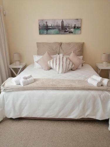 a large white bed with two towels on it at Villa Monique Self Catering Apartment in Sedgefield