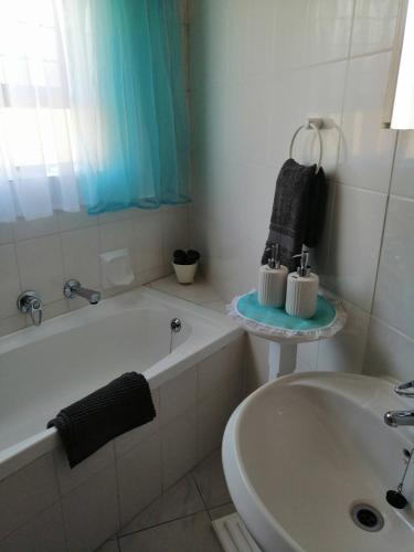 uma casa de banho branca com uma banheira e um lavatório em Villa Monique Self Catering Apartment em Sedgefield