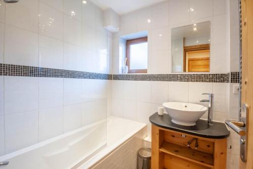 une salle de bain avec une baignoire et un lavabo et une baignoire tubermottermott dans l'établissement Christiania 4, à Morzine