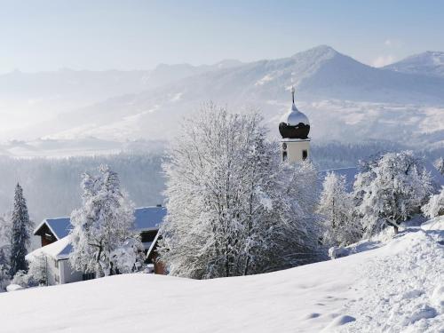 a church with a snow covered tower in the mountains at Ferienhaus Troy in Doren
