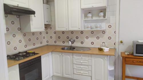 a kitchen with white cabinets and a sink at Corazón de Ponteareas in Ponteareas