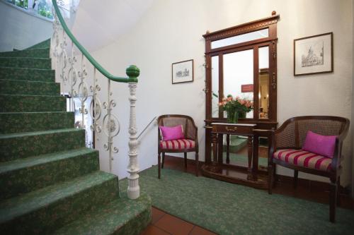 a staircase with two chairs and a table and a mirror at Hotel Kurpfalzstuben in Mannheim