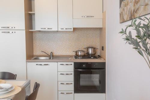 a kitchen with a stove, sink, and cabinets at Residence Le Fontane in Villasimius