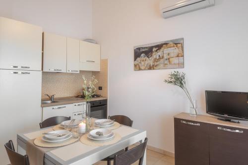 a kitchen with a table with chairs and a television at Residence Le Fontane in Villasimius