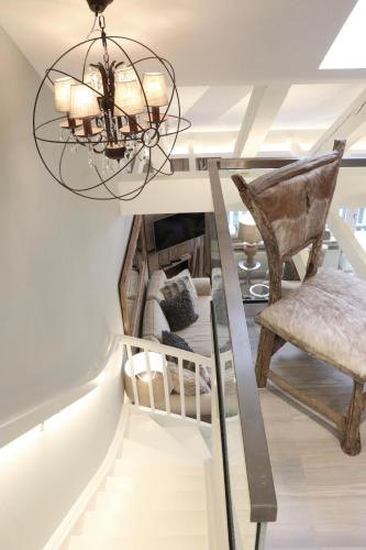 a staircase with a chandelier and a chair at HOME Suites Maisonette mit Sauna in Braunlage