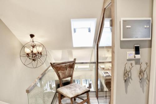 a glass staircase with a chair and a chandelier at HOME Suites Maisonette mit Sauna in Braunlage