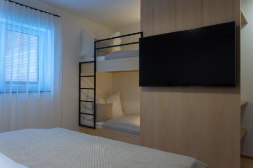 a bedroom with a bunk bed and a flat screen tv at Bergzeit Gosau in Gosau