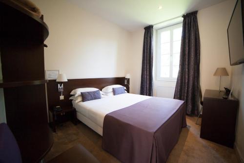 a bedroom with a bed and a window at Hotel La Beauze in Aubusson