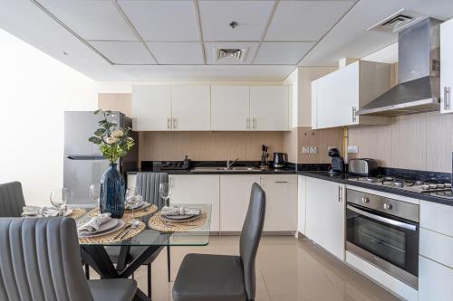 a kitchen with white cabinets and a table with chairs at HiGuests - Luxury Apartment in the Iconic Park Towers in Dubai