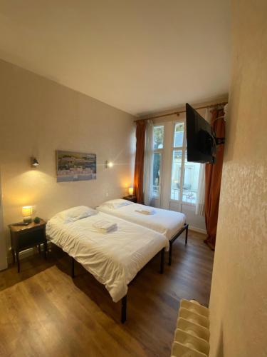 a bedroom with two beds and a flat screen tv at Chez Benjamin - Centre d'Azay le Rideau in Azay-le-Rideau