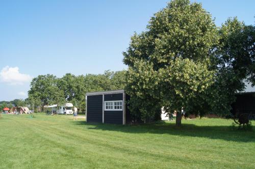 a small black shed in a field with a tree at Hoeve Linnerveld XL in Sint Odiliënberg