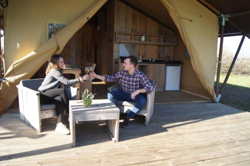 a man and woman shaking hands in front of a tent at Hoeve Linnerveld XL in Sint Odiliënberg