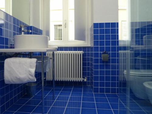 a blue tiled bathroom with a sink and a radiator at New Fontana Rooms in Como