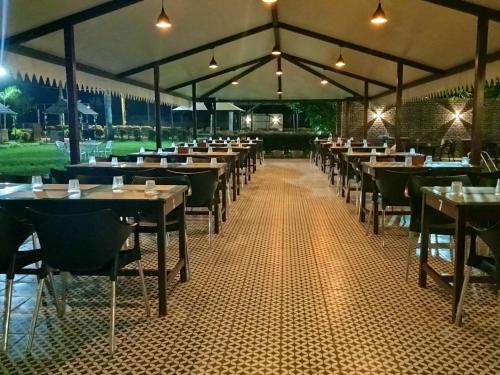 un comedor con mesas, sillas y luces en Vistar Resort & Hotels, en Bangalore