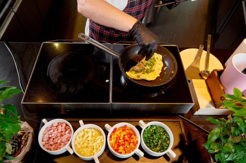 a person cooking food in a pan on a stove at Sound Garden Hotel Airport in Warsaw