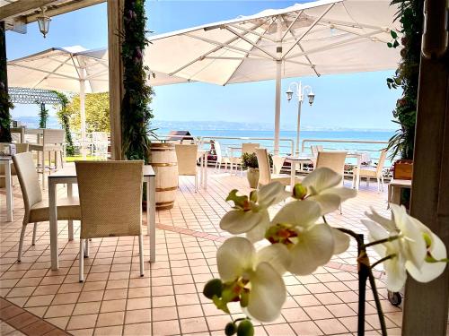 a patio with tables and chairs and an umbrella at Hotel Aquila D'Oro Desenzano in Desenzano del Garda