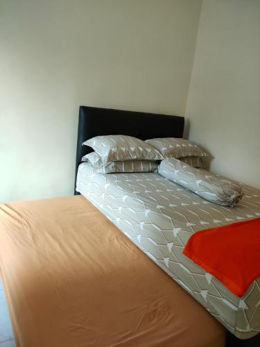 a bed with two pillows and a red blanket on it at Villa Amadeo in Batu