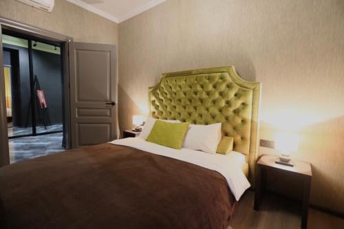 a bedroom with a large bed with a green headboard at Apartments Lux in city center Lviv in Lviv