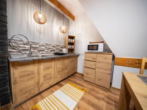 a kitchen with wooden cabinets and a microwave at Apartamenty Małgorzatka in Zakopane