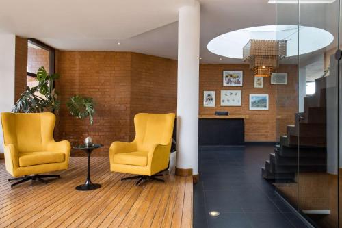 a lobby with two yellow chairs and a staircase at Radisson Hotel Tamboho Waterfront Antananarivo in Antananarivo